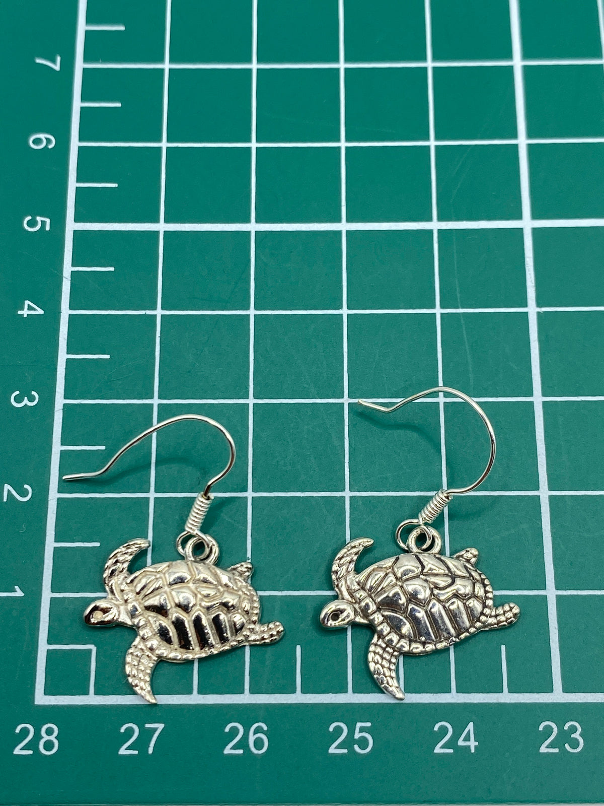 Aretes de tortuga marina colgando de gancho de plata, vista lateral