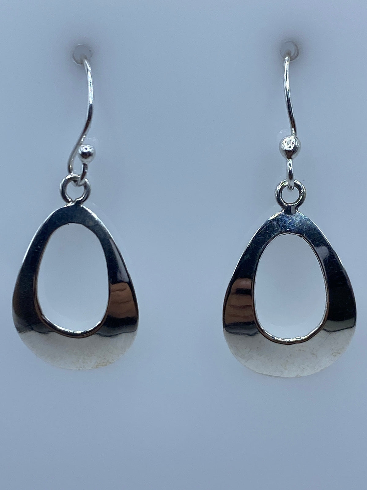 Aretes de plata calado en forma de gota, diseño minimalista sobre fondo gris