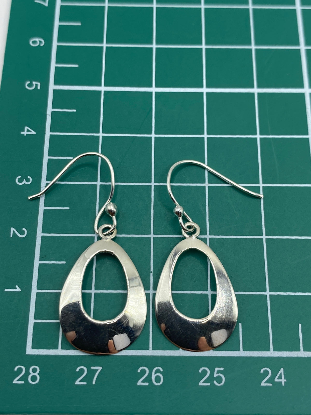 Aretes colocados en escala de medida mostrando largo de 1.8 cm