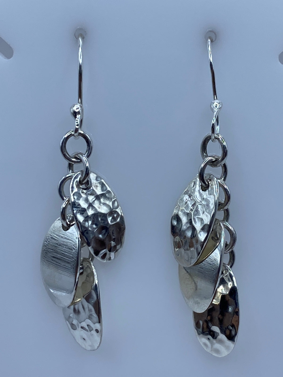 Aretes de plata 925 con eslabones combinados, acabado pulido y martillado, colgando sobre fondo gris