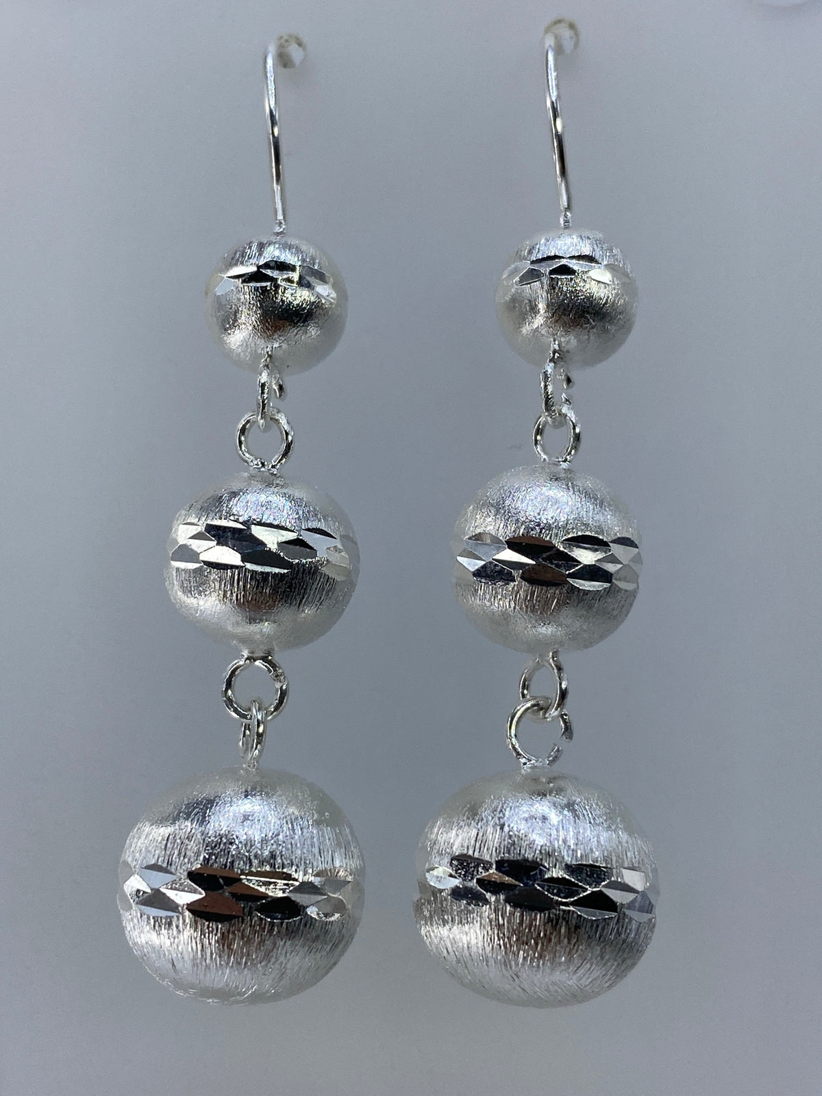 Vista frontal del par de aretes de plata 925 mostrando las esferas texturadas