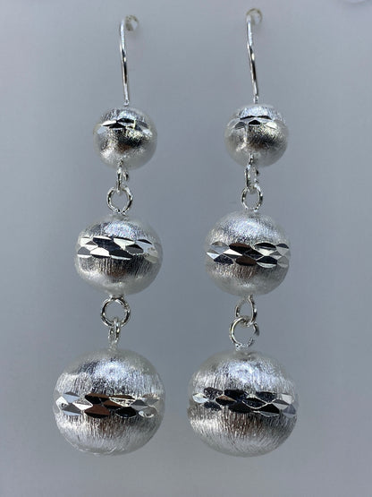 Vista frontal del par de aretes de plata 925 mostrando las esferas texturadas