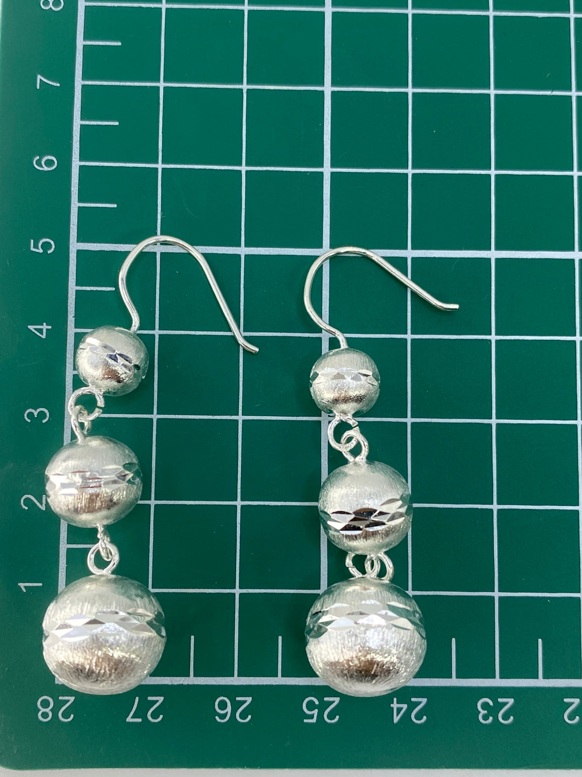 Aretes sobre fondo blanco con el sello 925 visible en los ganchos