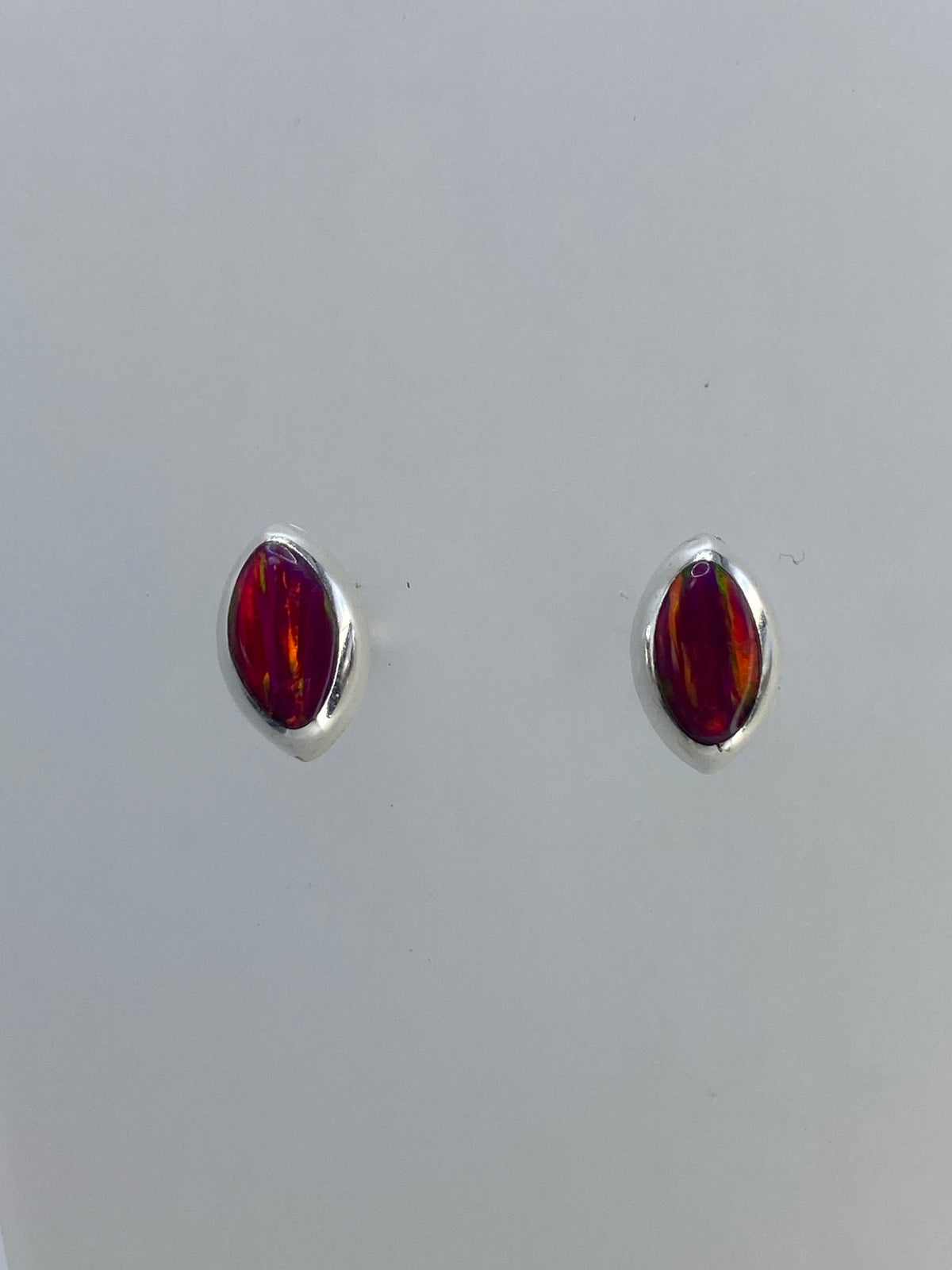 Vista frontal de aretes ópalo fuego mostrando los tonos rojo, naranja y verde