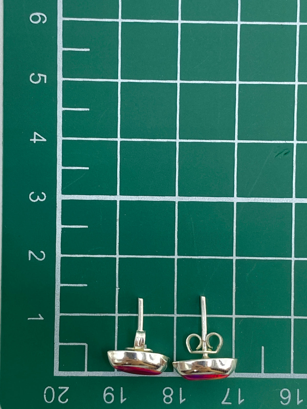 Aretes sobre fondo blanco con escala de medida en centímetros