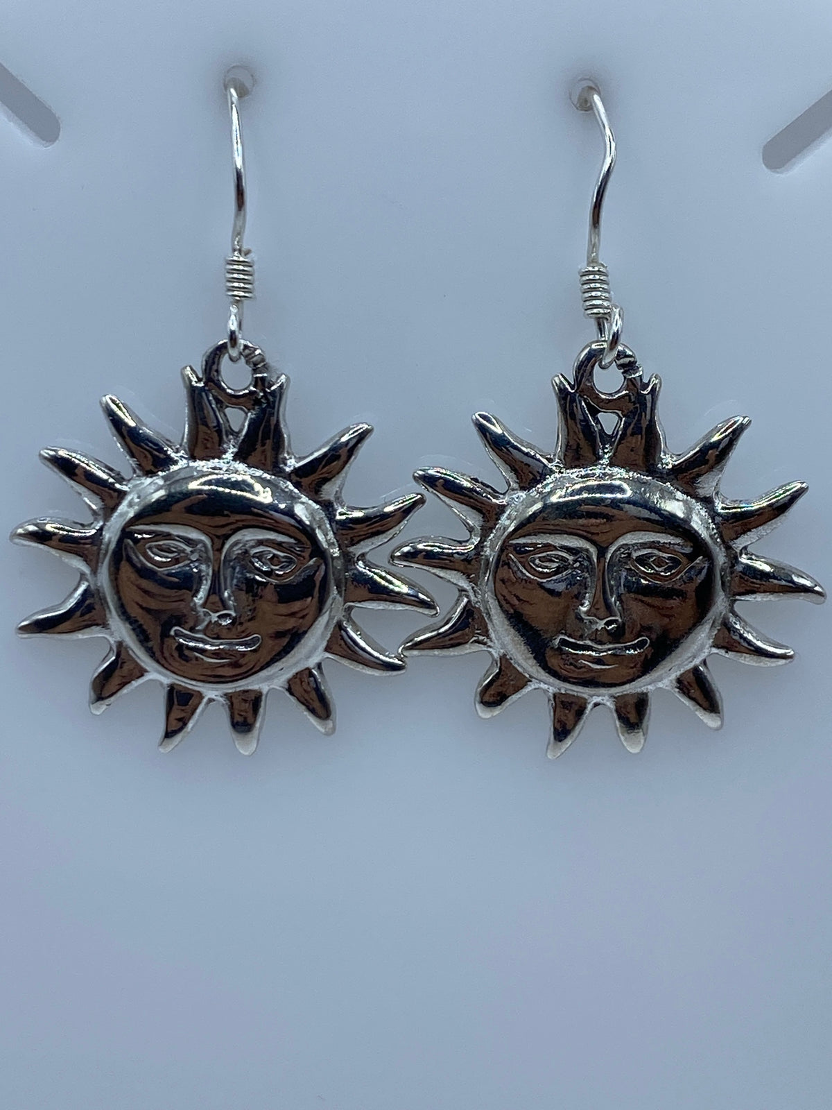 Detalle de un arete sol mostrando el rostro grabado y el acabado pulido de la plata