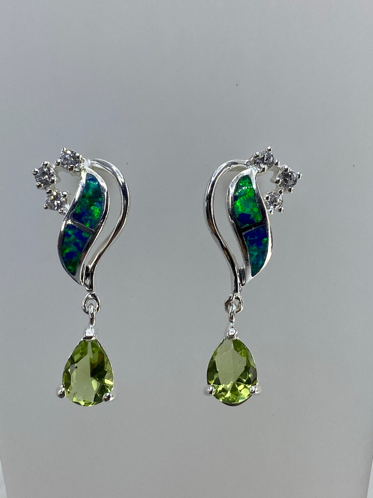 Detalle del engaste a mano del ópalo de fuego multicolor y la circonia verde en plata 925