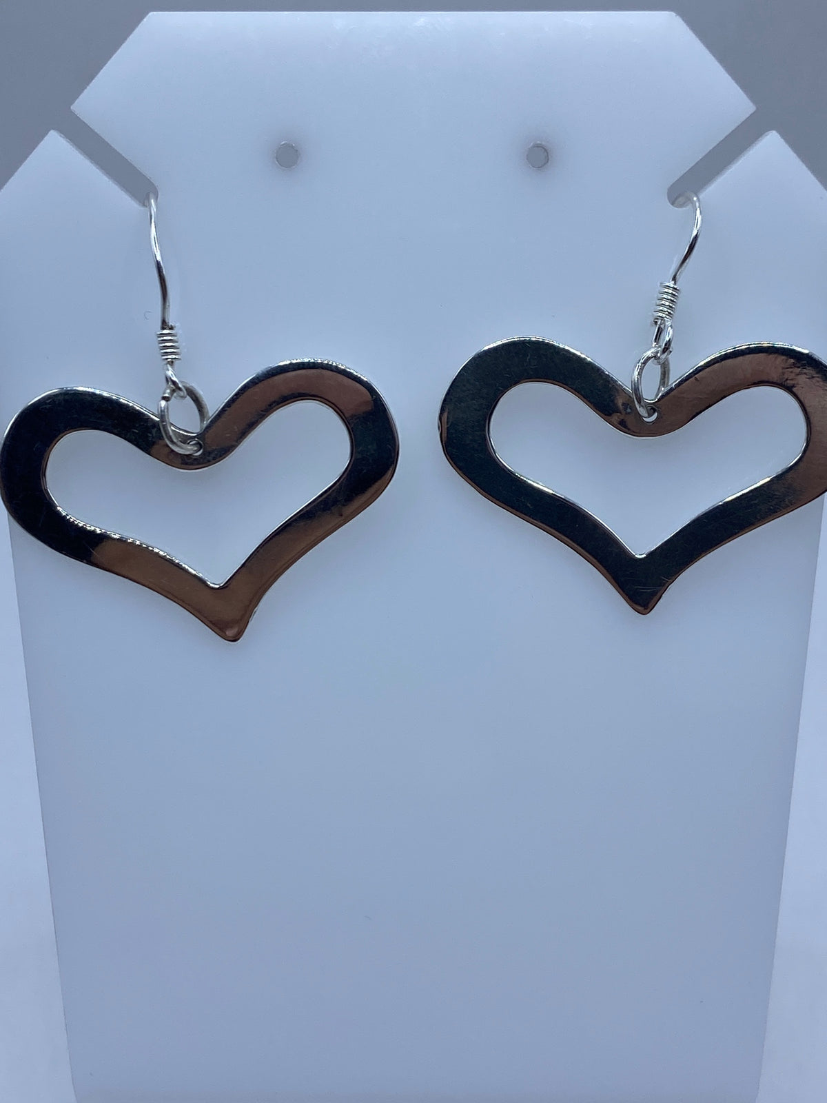 Detalle frontal de los aretes corazón mostrando el patrón de calado y el acabado brillante de la plata 925