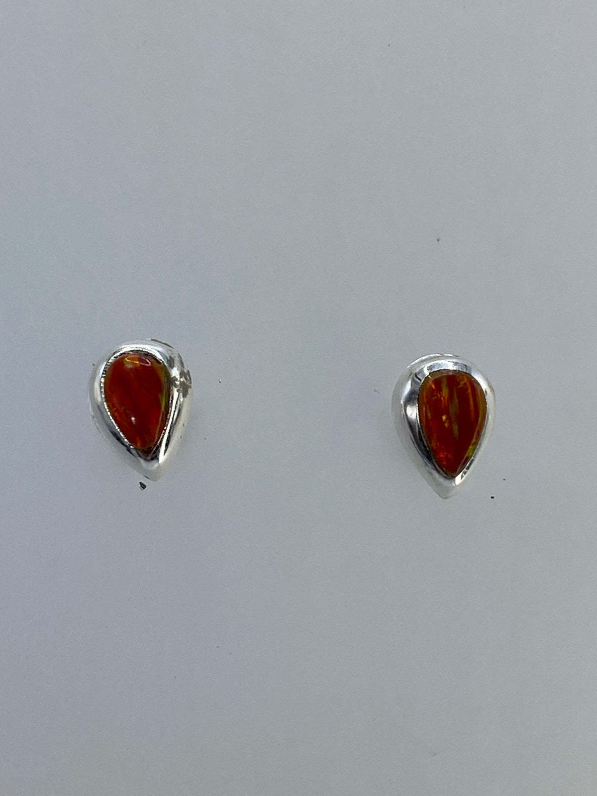 Aretes de plata con ópalo de fuego multicolor en tonos naranja y rojo, vistos de frente
