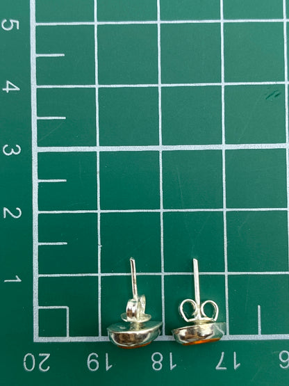 Aretes con ópalo de fuego multicolor sobre fondo gris, mostrando el acabado pulido de la plata