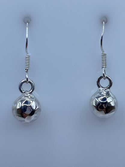 Aretes de plata facetados en par, mostrando el brillo de la faceta pulida