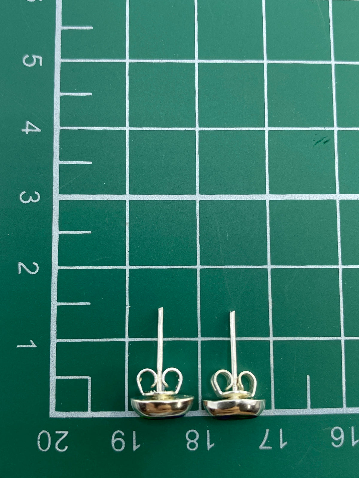 Aretes de ópalo de fuego sobre fondo gris mostrando el Quinto 925