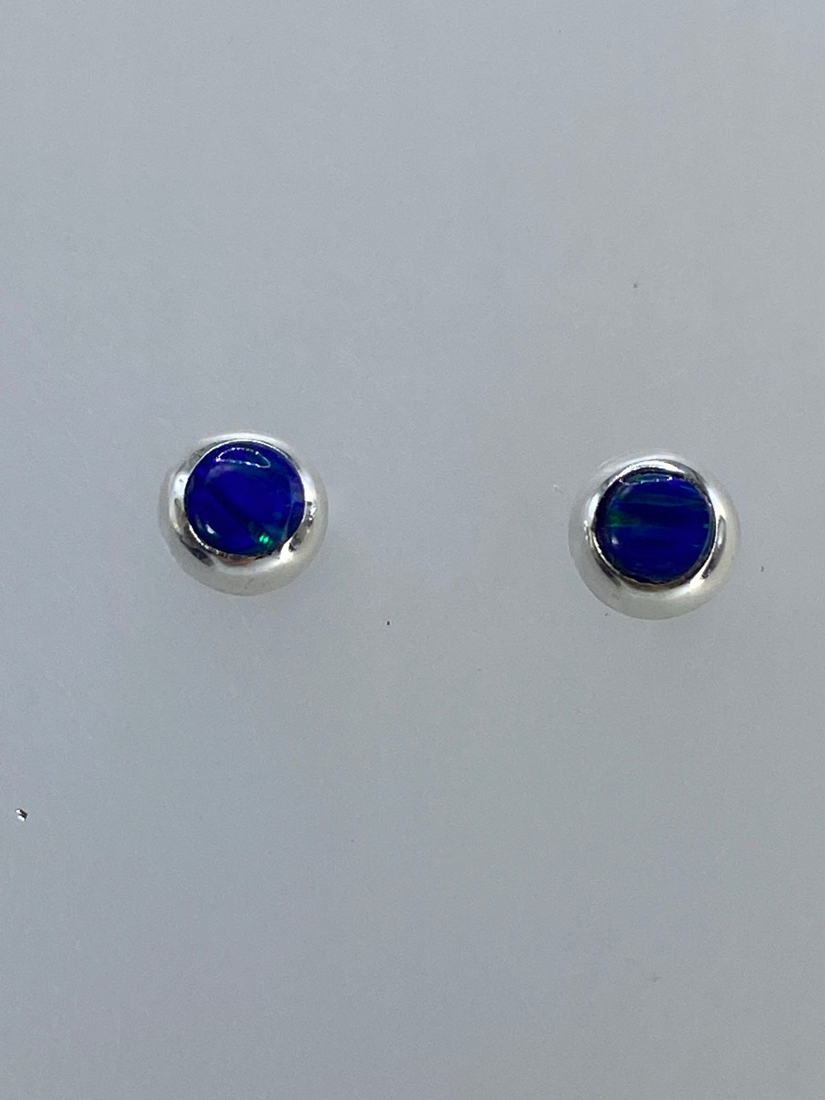 Par de aretes de ópalo de fuego mostrando los colores iridiscentes: rojo, naranja, verde y azul