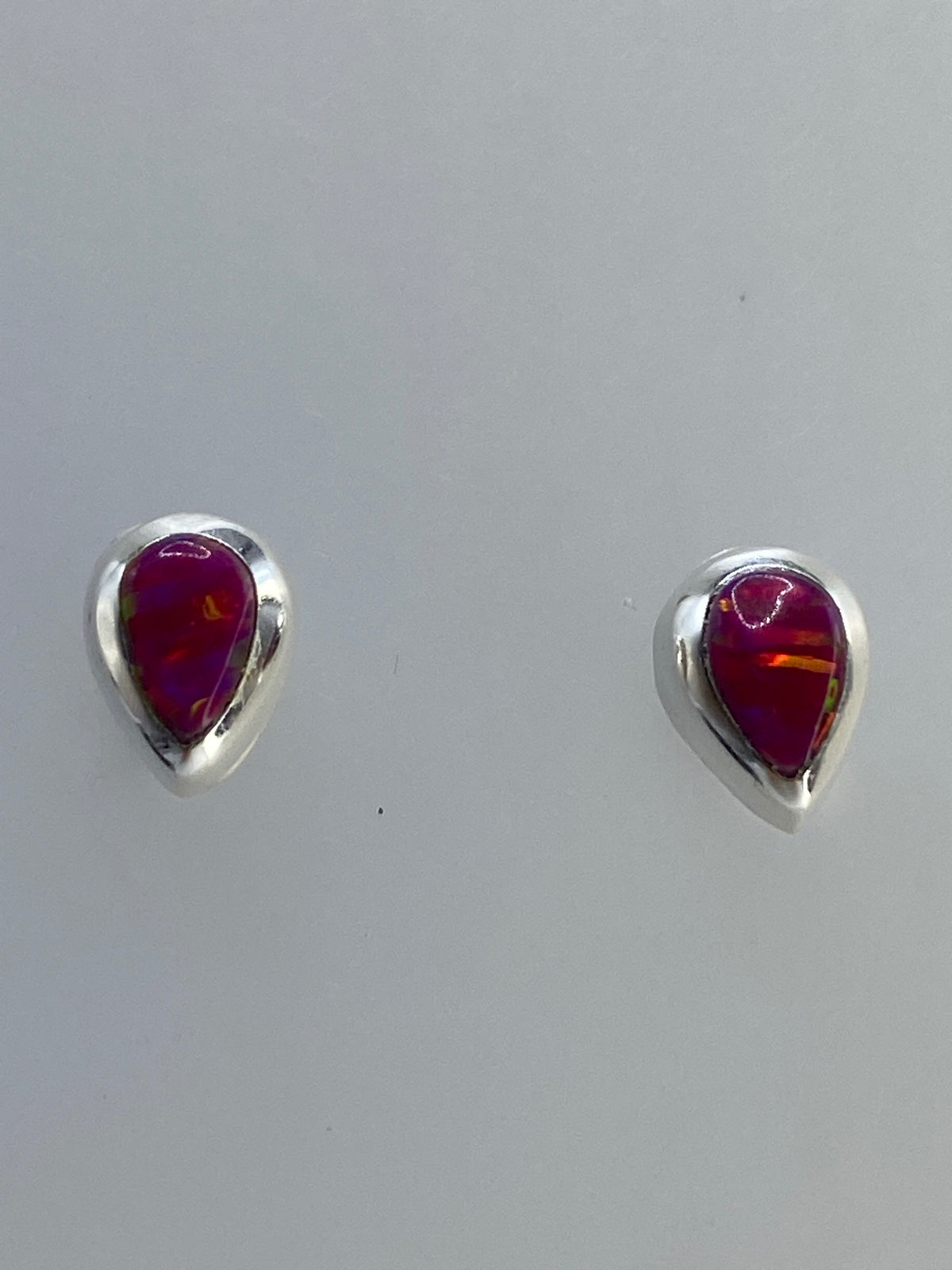 Aretes de plata con ópalo de fuego multicolor mostrando tonos rojo, naranja y amarillo