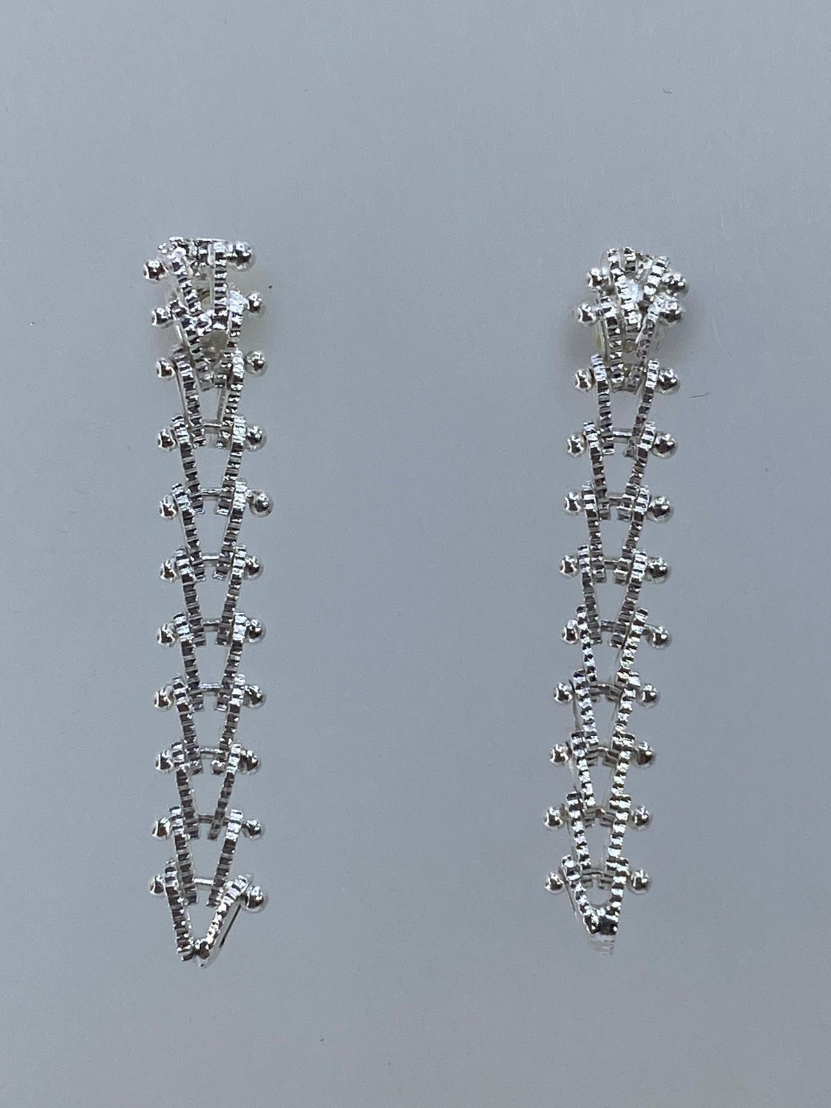 Par de aretes largos minimalistas de plata 925 sobre fondo gris