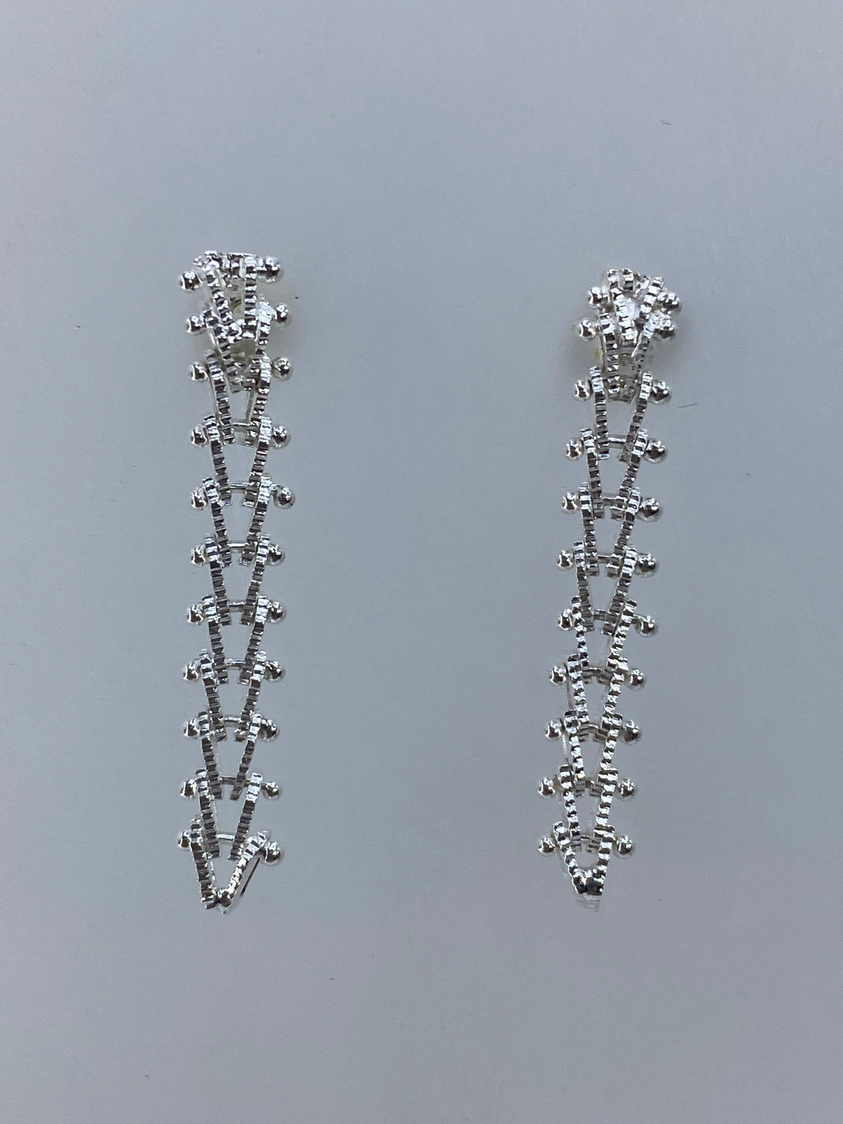 Detalle de los aretes Taxco mostrando el pulido brillante y la línea recta
