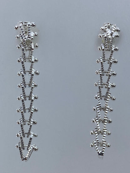 Aretes largos con cierre visible en fotografía con escala de medida