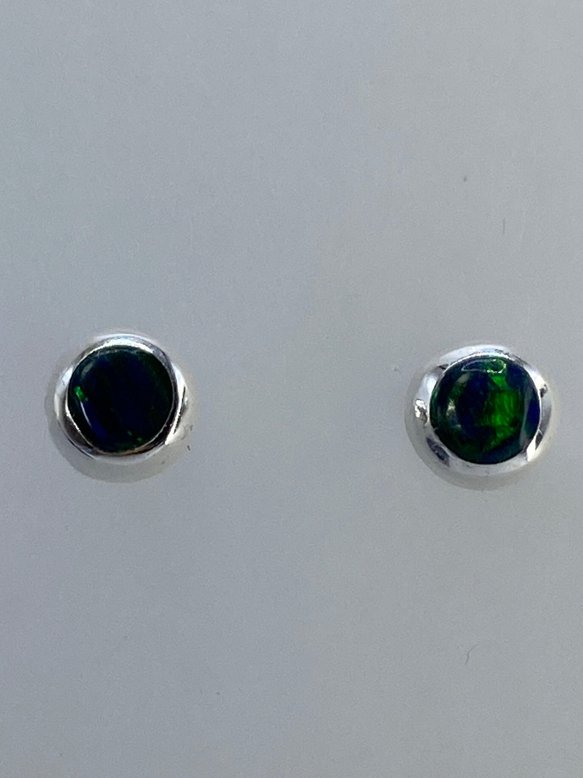 Aretes de plata 925 con ópalo de fuego multicolor, vistos de frente sobre fondo blanco