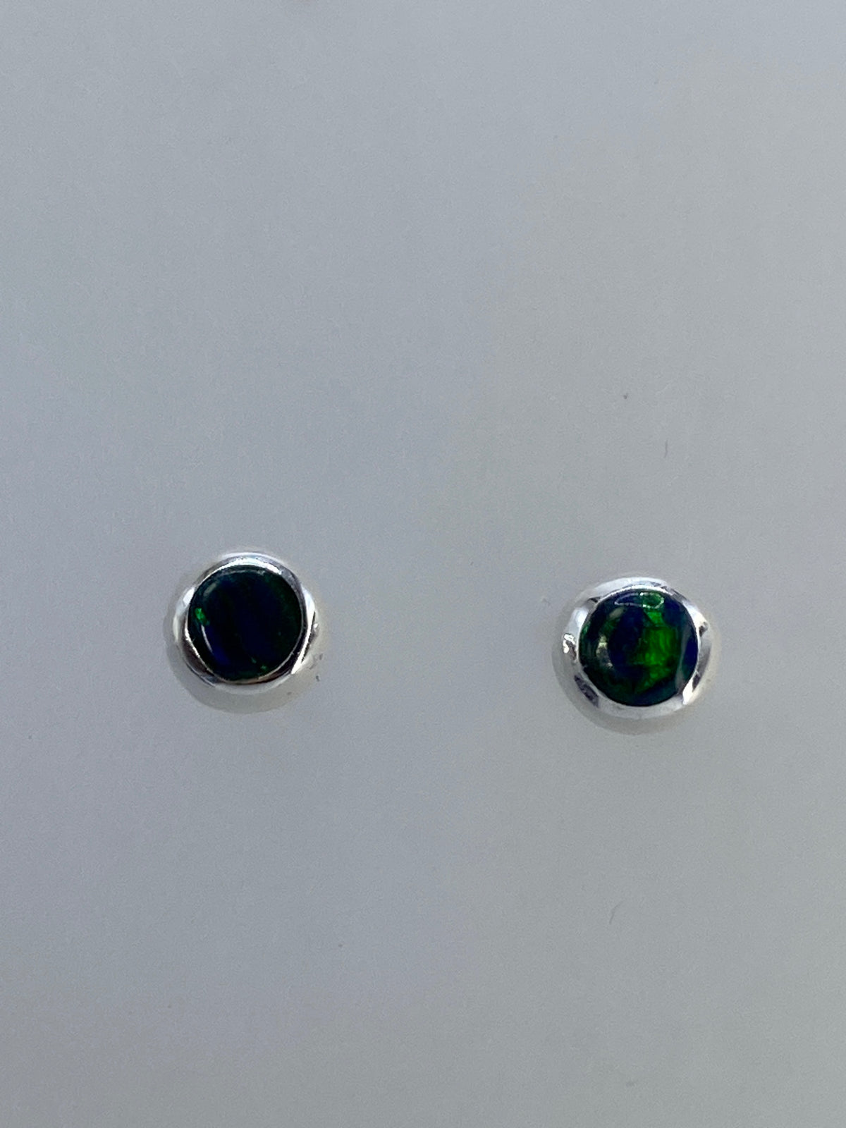 Par de aretes compactos con piedra roja anaranjada y destellos verdes azulados