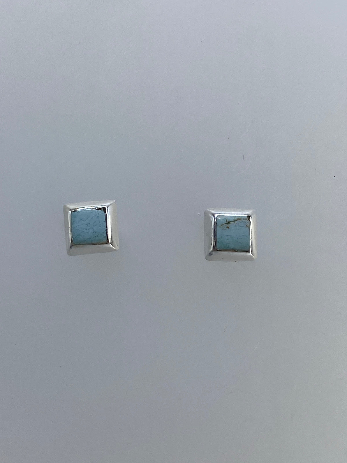 Aretes minimalistas de plata con piedra, ángulo lateral mostrando el grosor