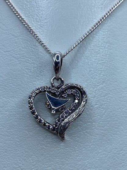 Dije corazón de plata sobre regla métrica mostrando 2.1 cm de largo