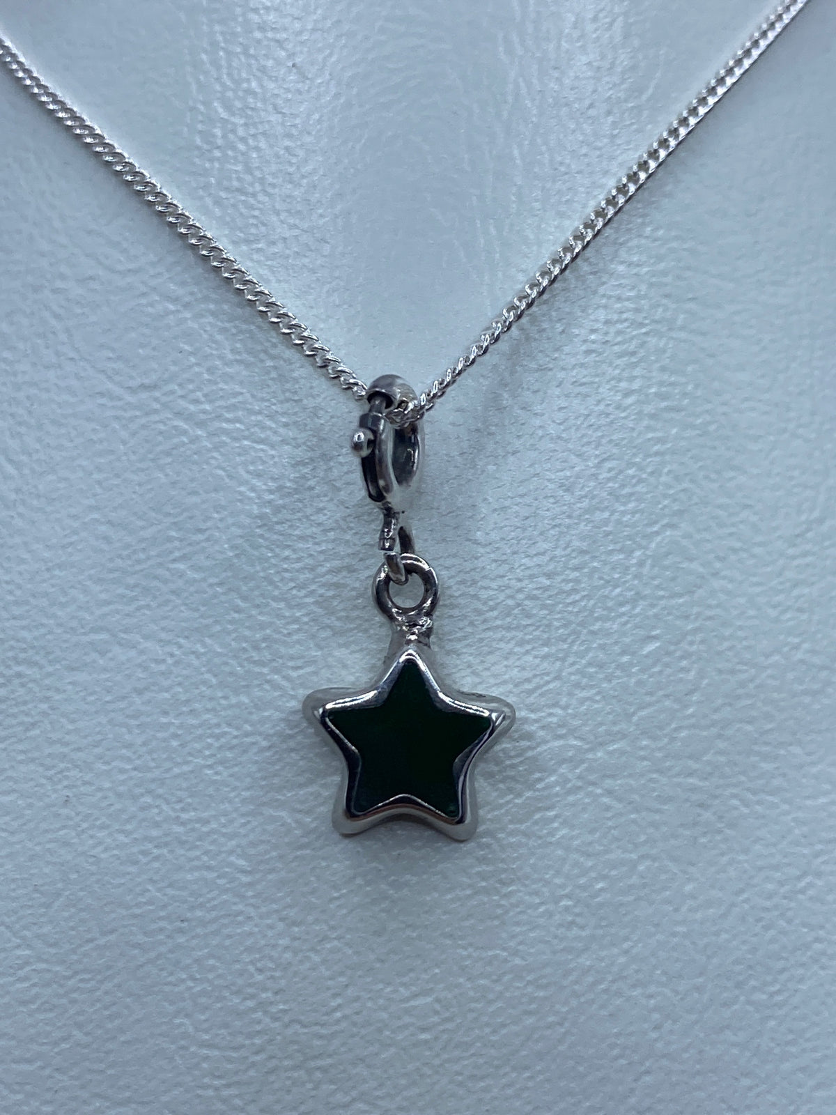 Dije de estrella de plata 925 con piedra verde engastada, colgando de una cadena