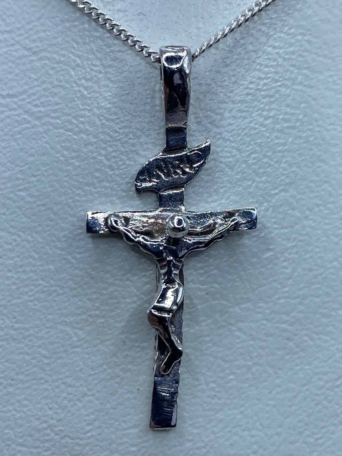 Vista lateral del dije de Jesús crucificado sobre regla de medición, 3.2 cm