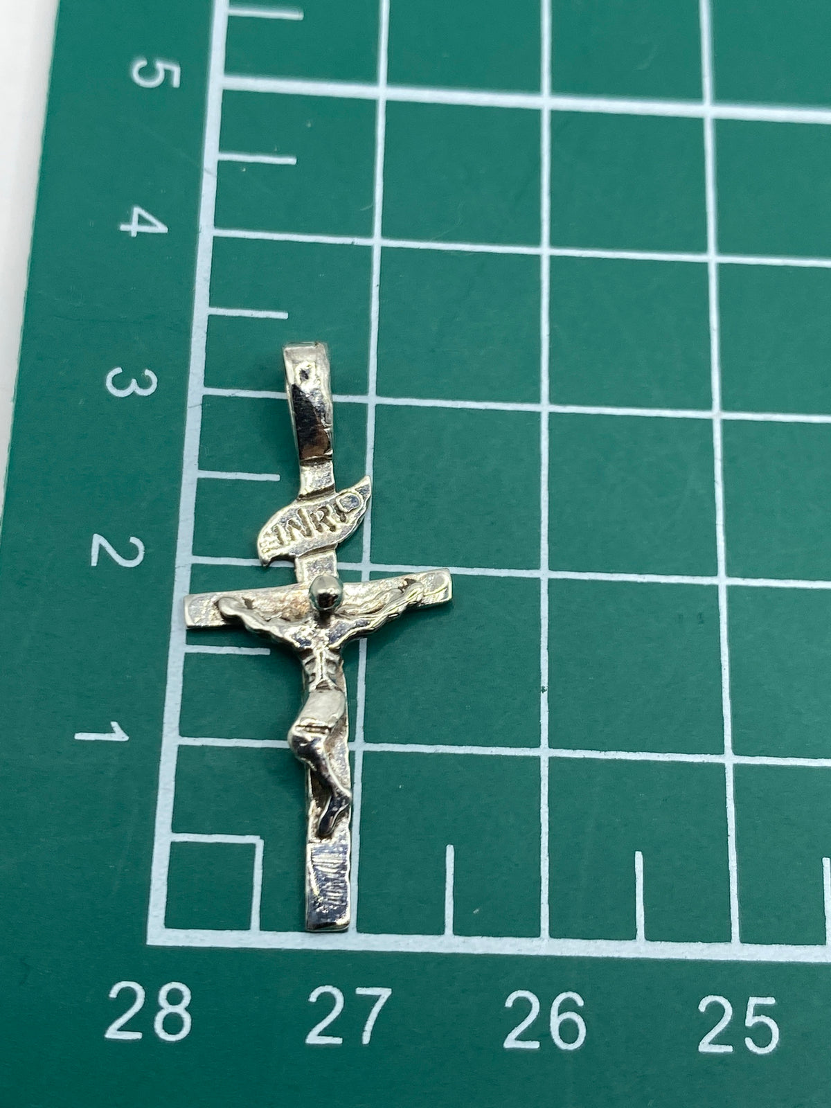 Dije de crucifijo pesado en escala de precisión, 1.33 gramos