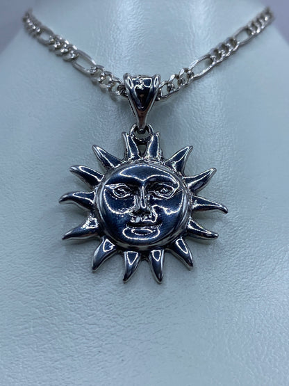 Detalle del dije de sol mostrando el labrado artesanal de los ojos y la boca