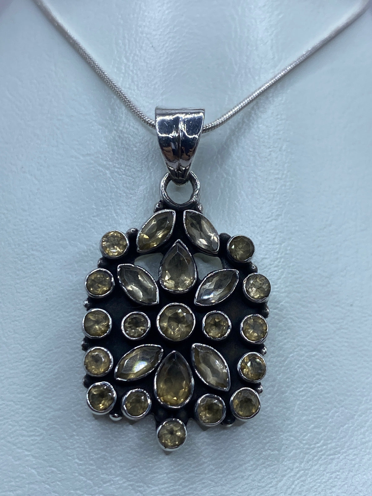 Dije de plata con circonia champaña engastada, colgando de cadena plateada