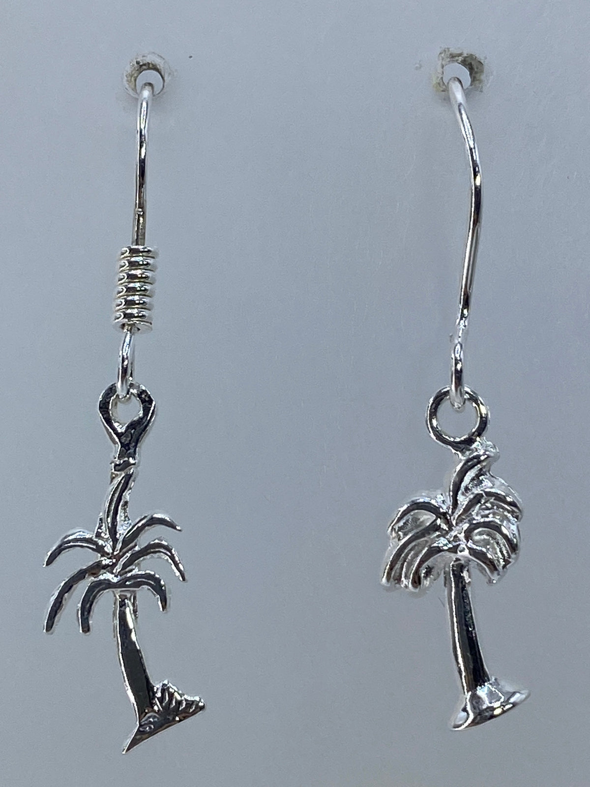 Aretes de plata palmera en la oreja, luciendo ligeros y minimalistas