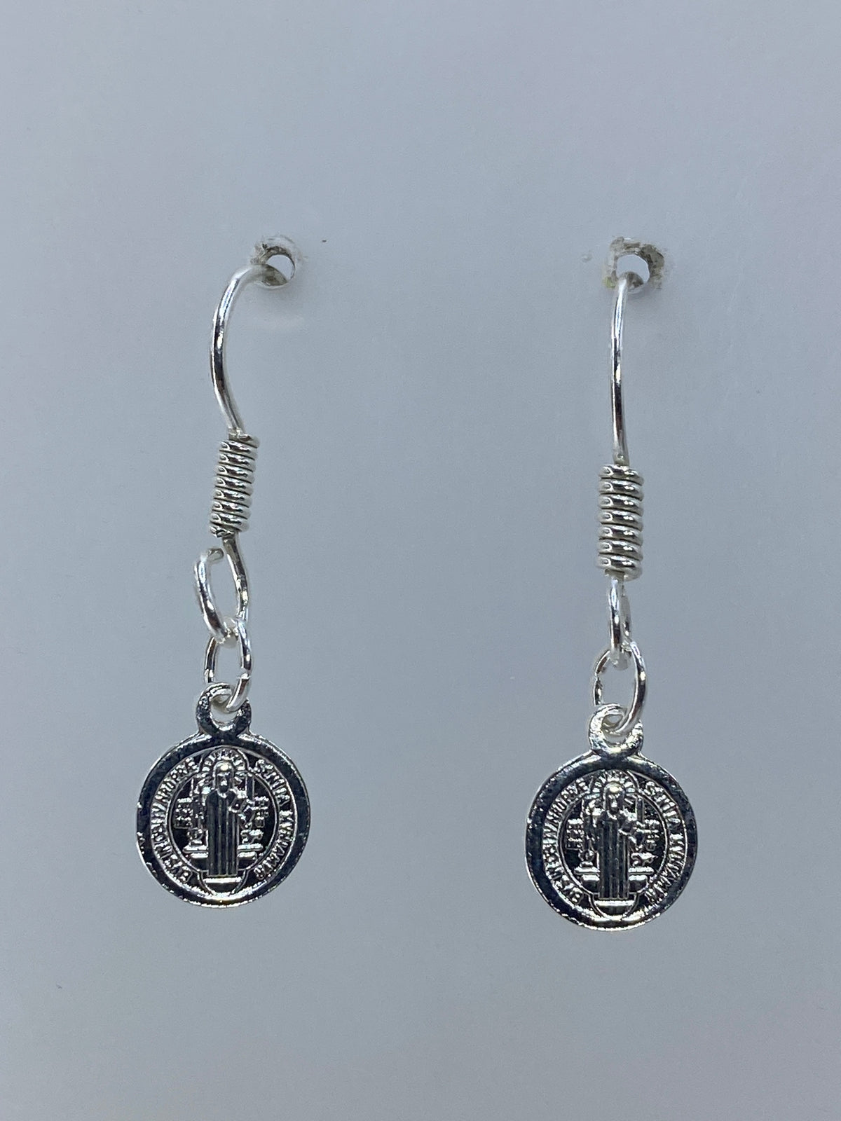 Par de aretes de plata 925 con medalla de San Benito repujada, colgando en gancho de seguridad