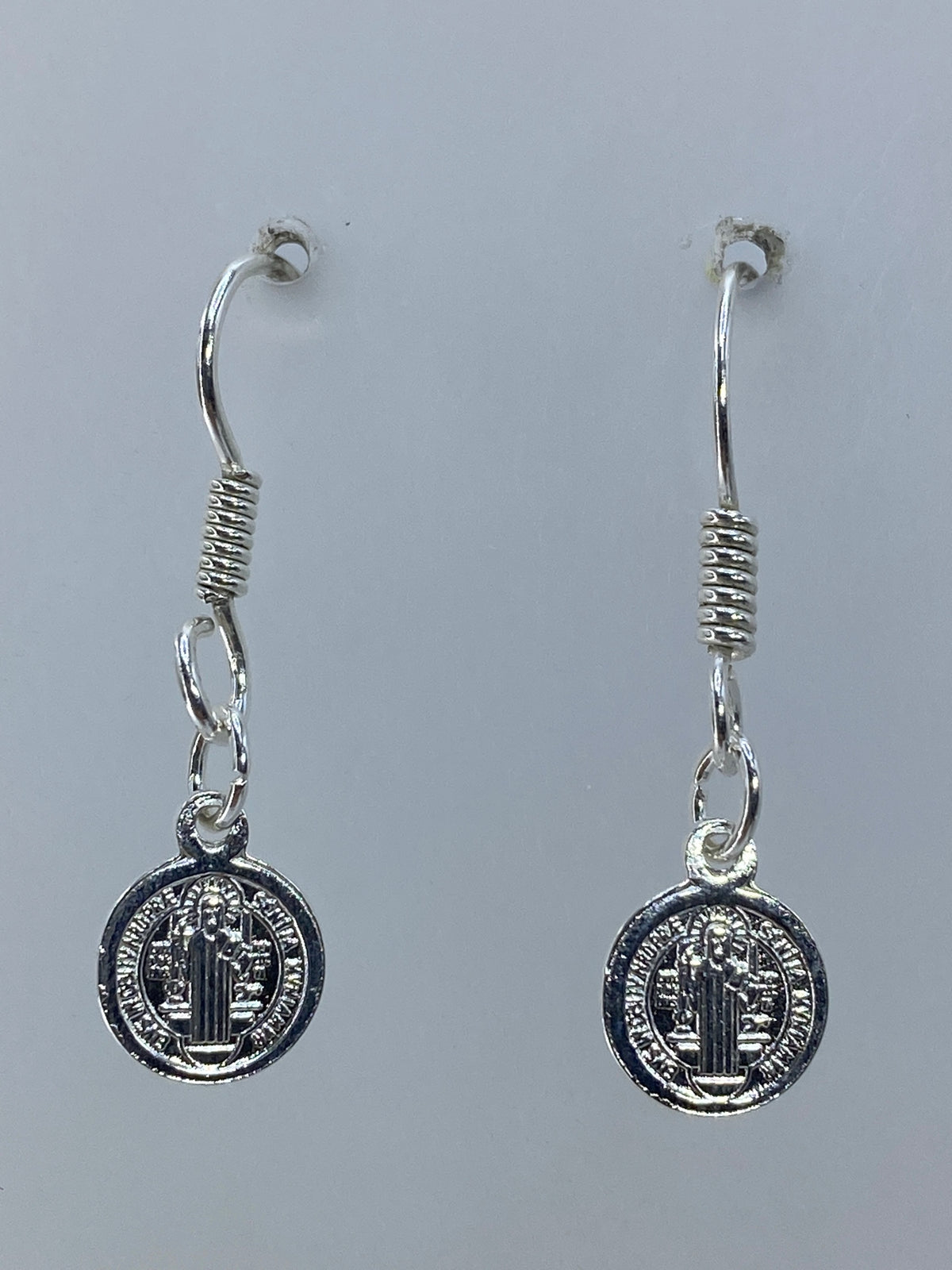 Detalle frontal de la medalla de San Benito con relieves repujados a mano en plata