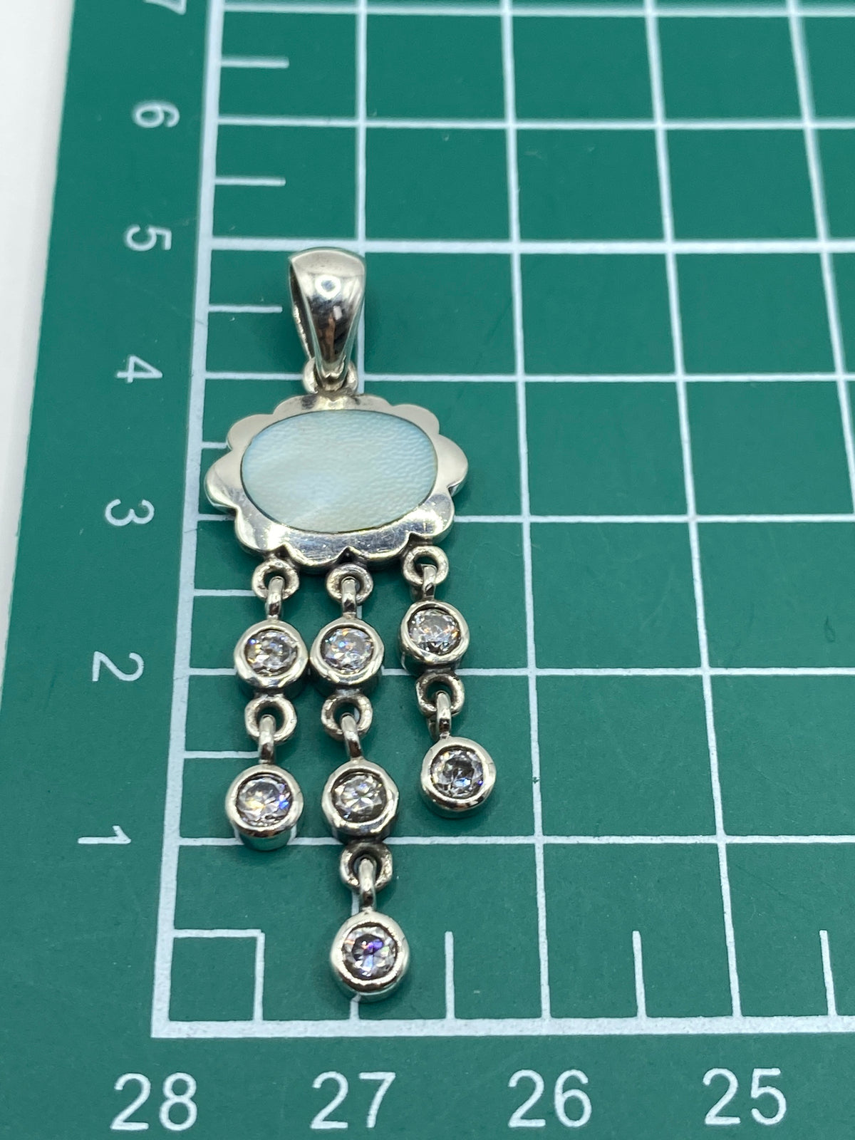 Dije de plata con circonia en escala de medición, verificando dimensiones de 4.5 cm