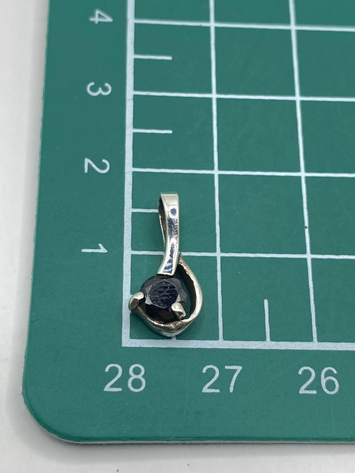 Dije sobre regla mostrando tamaño real de 1.5 cm de largo