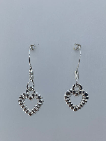 Detalle cercano del repujado: texturas y relieves de luz en los corazones de plata
