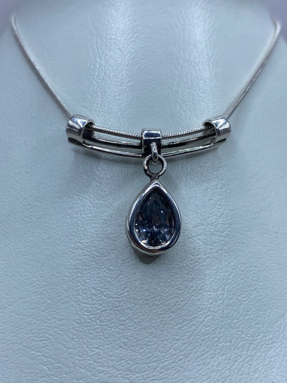 Detalle frontal del dije con circonia facetada reflejando luz, engastado en plata 925