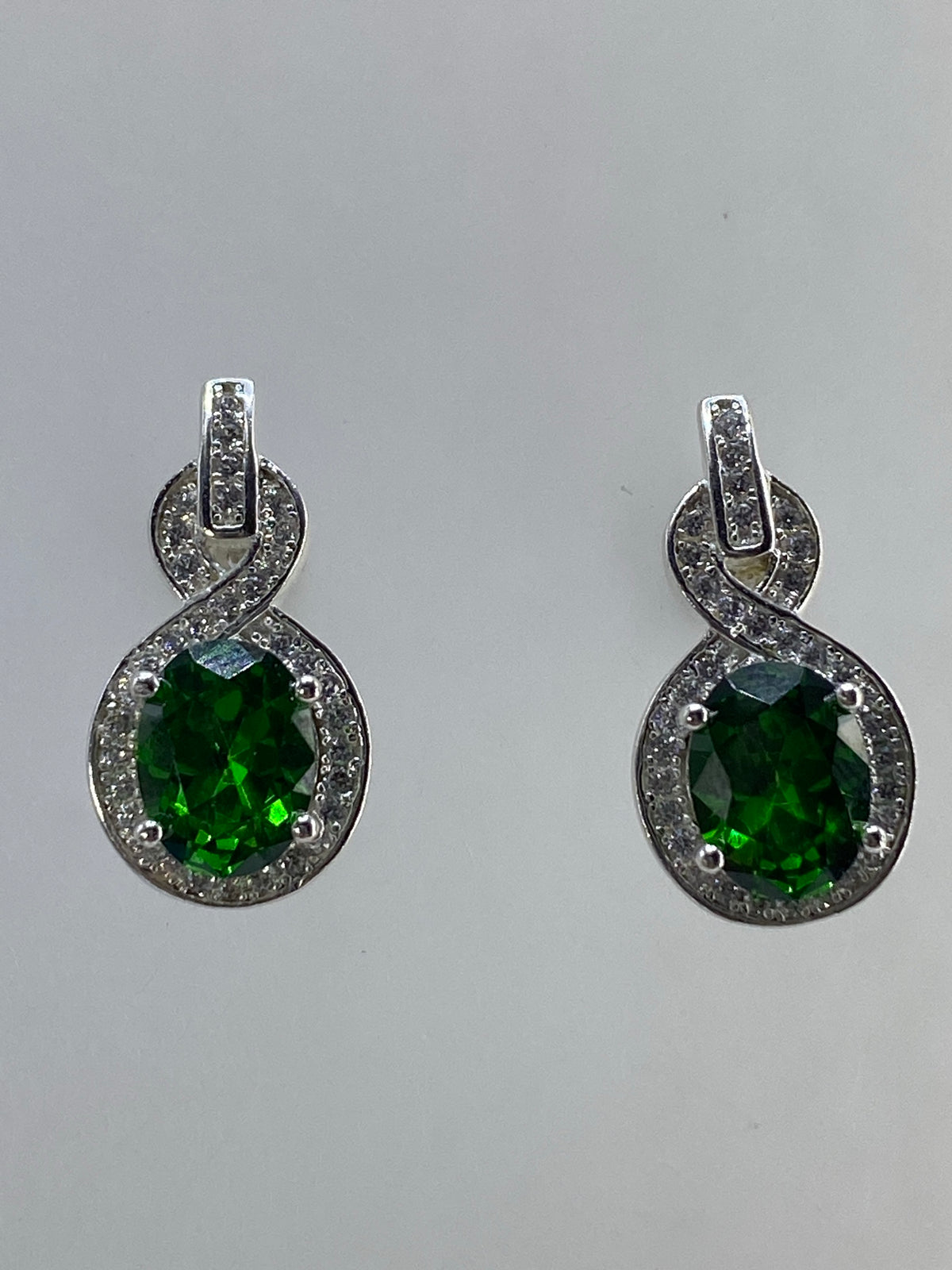 Aretes sobre fondo gris mostrando el brillo verde de la circonia