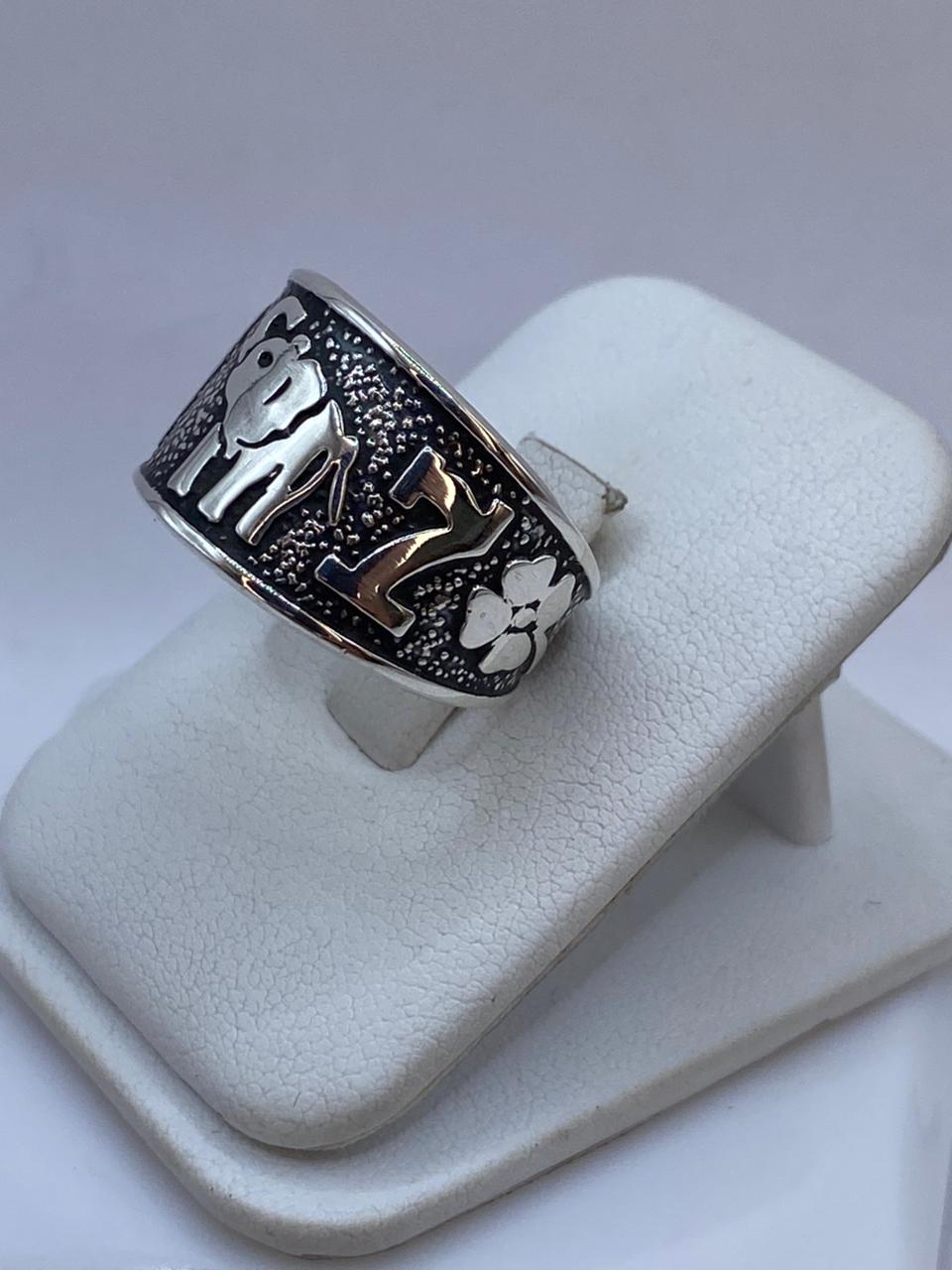 Anillo de plata .925 con cuatro símbolos de buena suerte en relieve sobre fondo oxidado negro — joyería mexicana artesanal Taxco