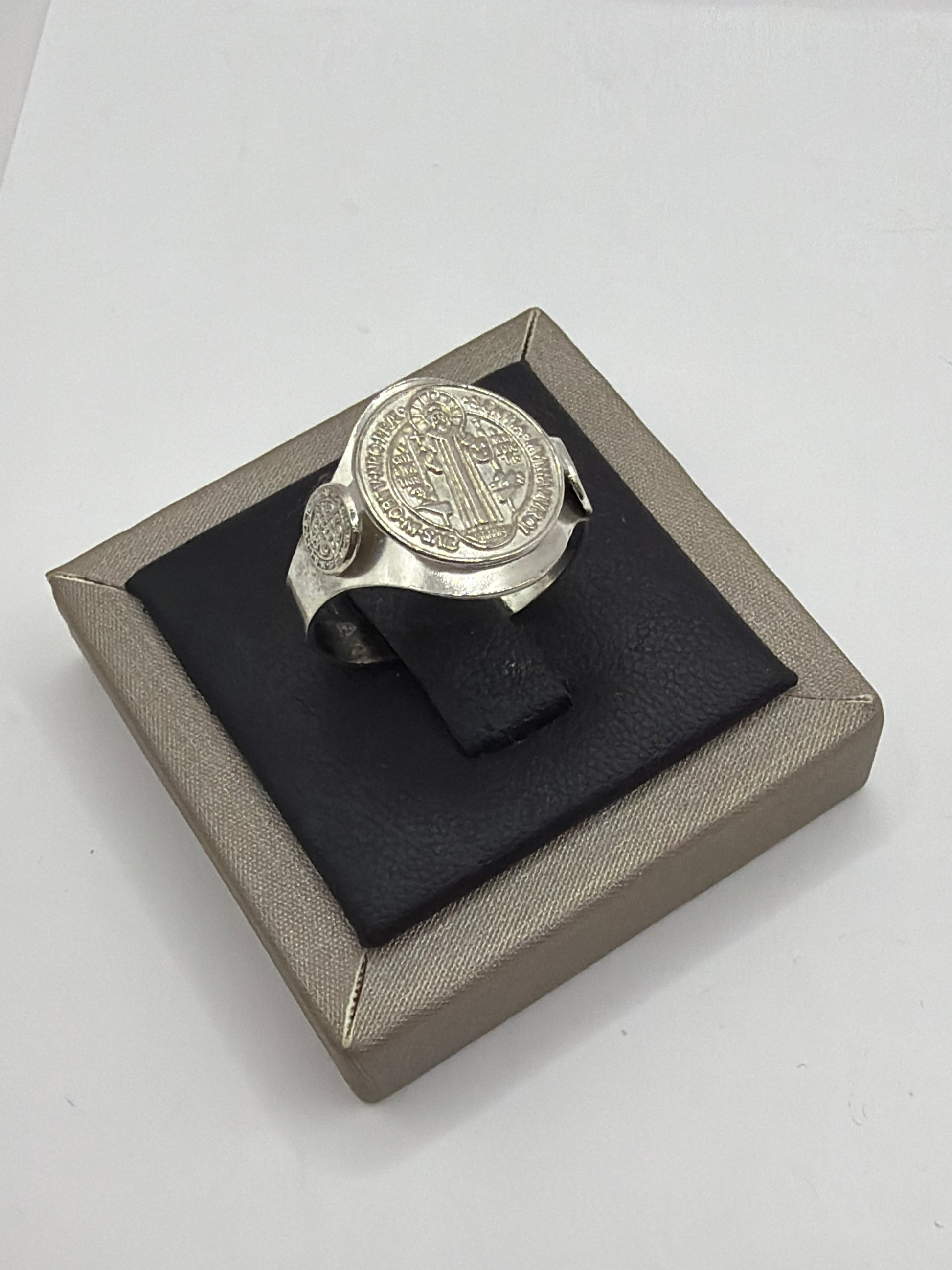 Anillo San Benito en plata .925 sobre caja de presentación, vista frontal con símbolo grabado en el bezel