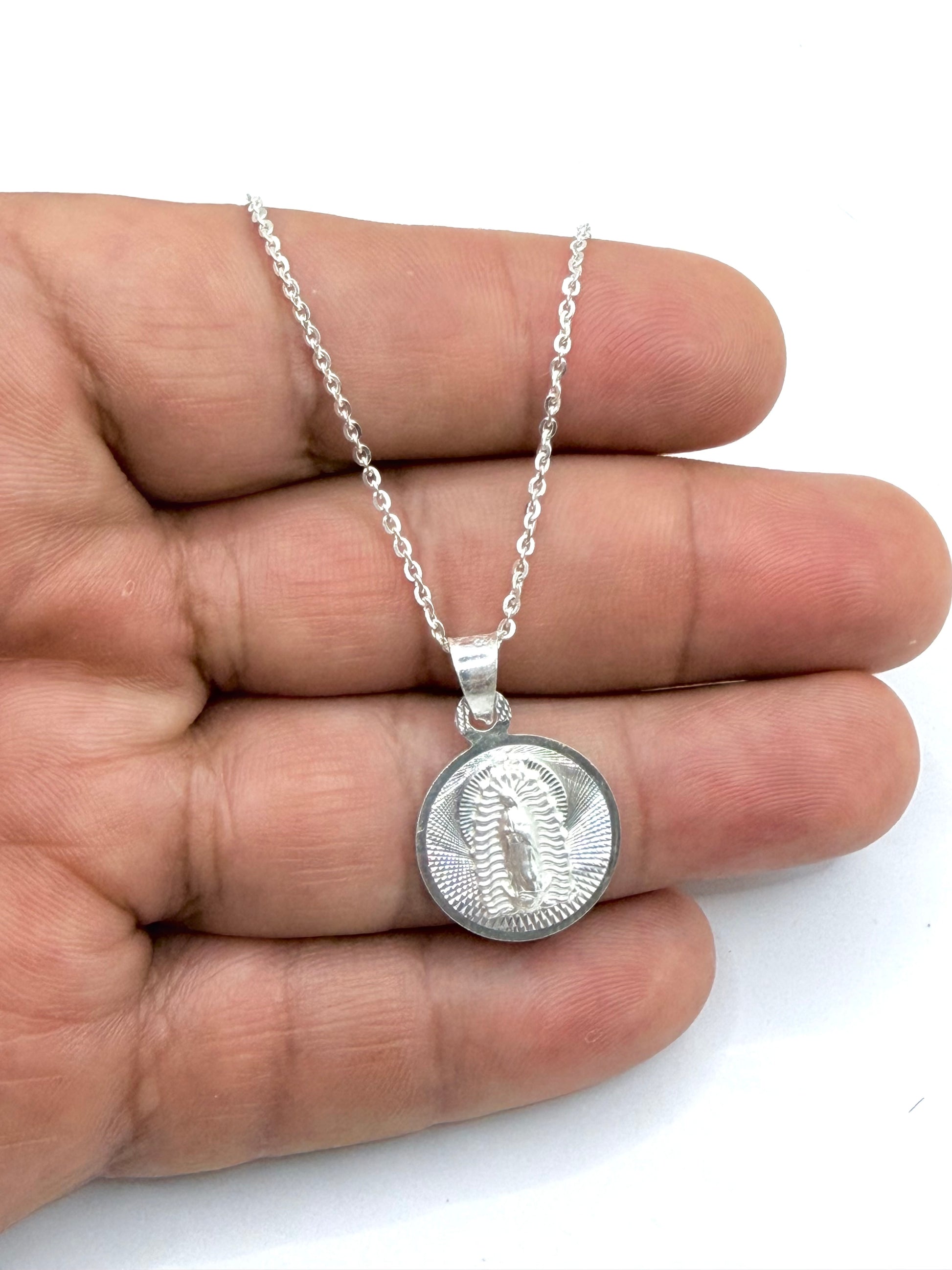 Collar completo en mano mostrando medalla y cadena de plata calibrada