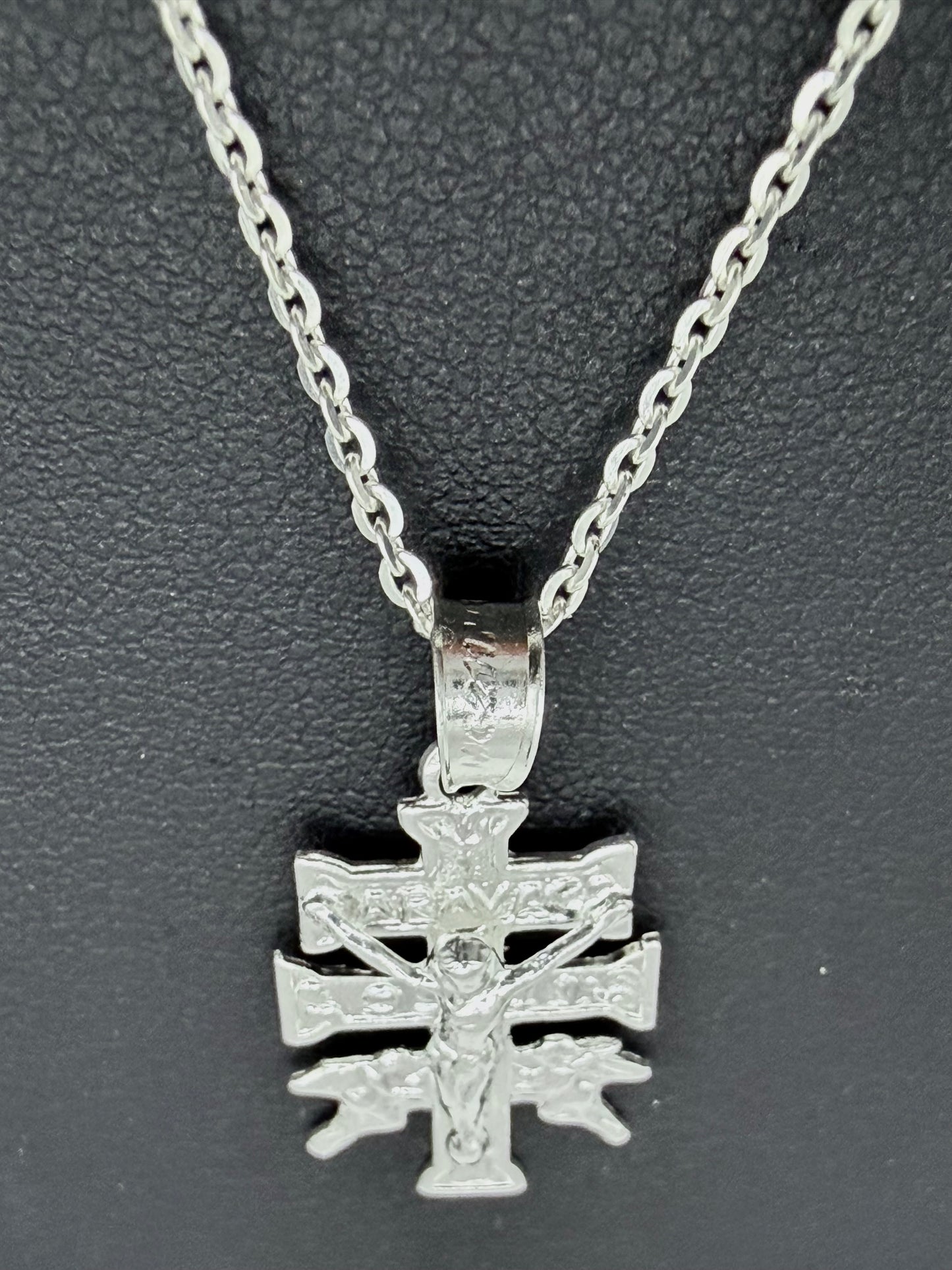 Detalle del dije Cruz de Carabaca en fundición de plata pura, mostrando relieves religiosos