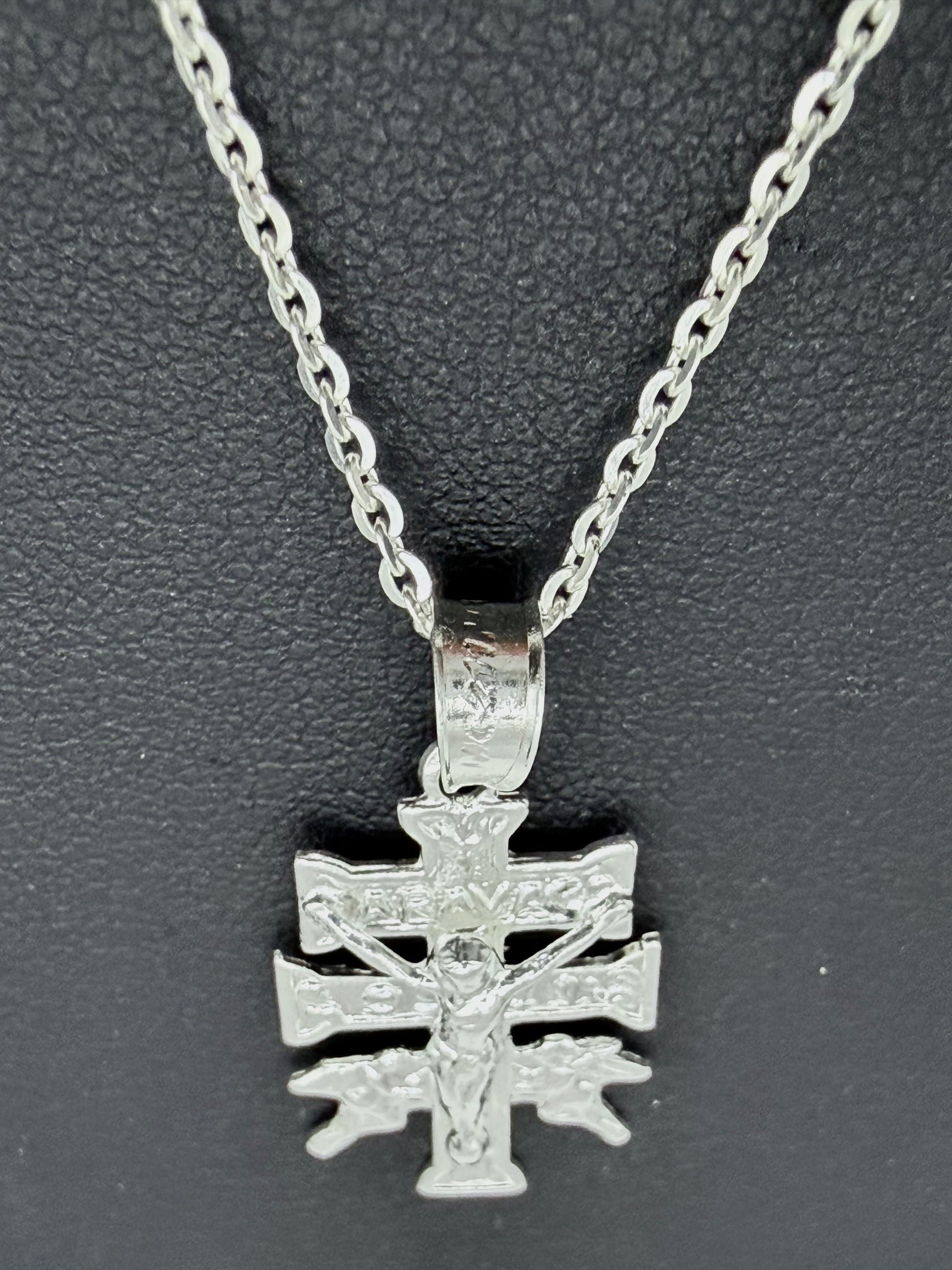 Detalle del dije Cruz de Carabaca en fundición de plata pura, mostrando relieves religiosos