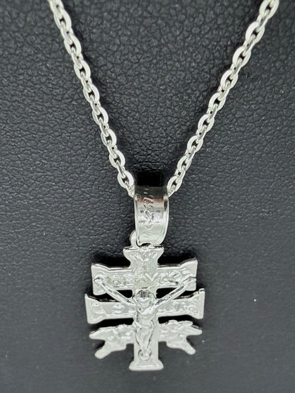 Detalle del dije Cruz de Carabaca en fundición de plata pura, mostrando relieves religiosos