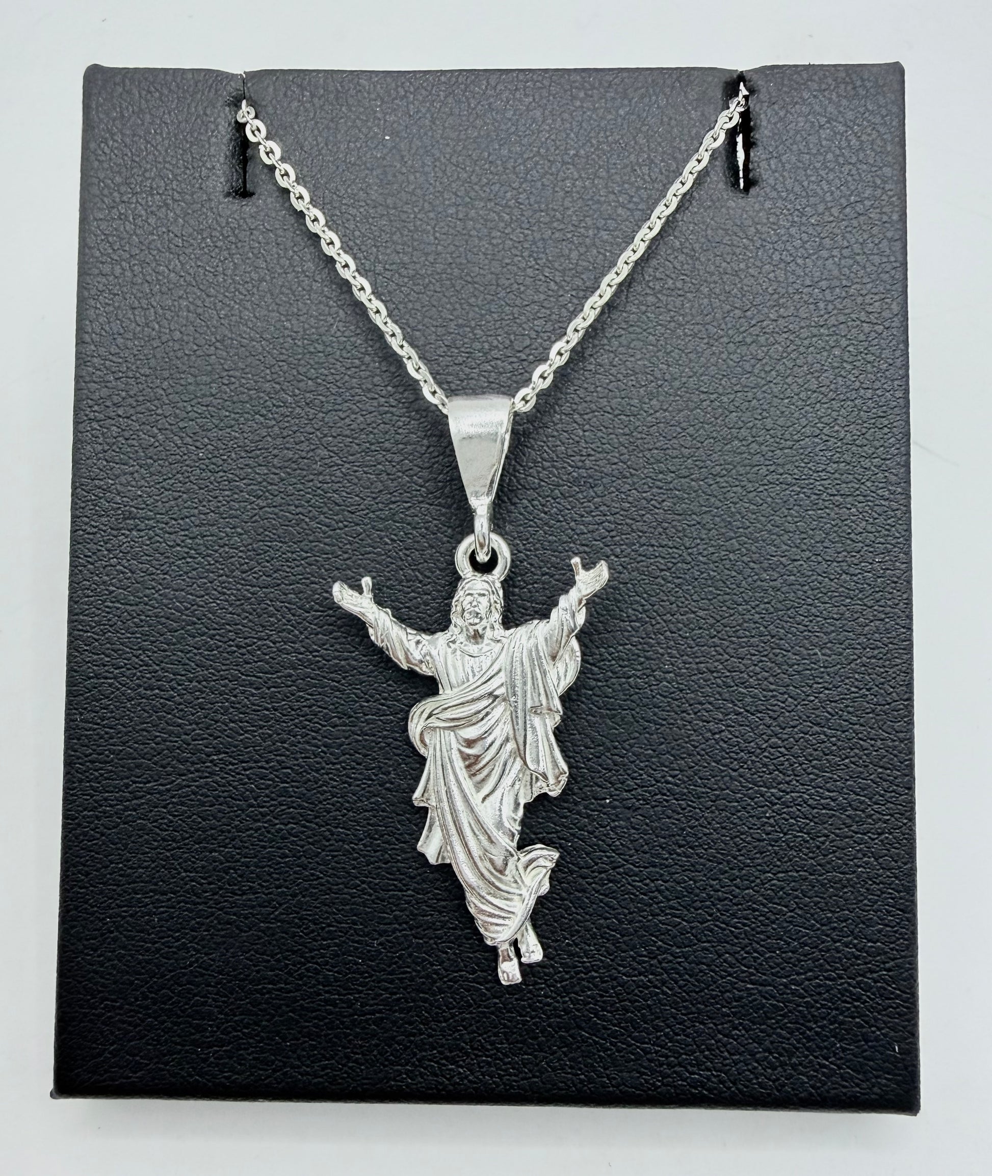 Collar Cristo de plata .925 sobre caja gris oscuro, cadena de eslabones rectangulares, Cristo con brazos elevados