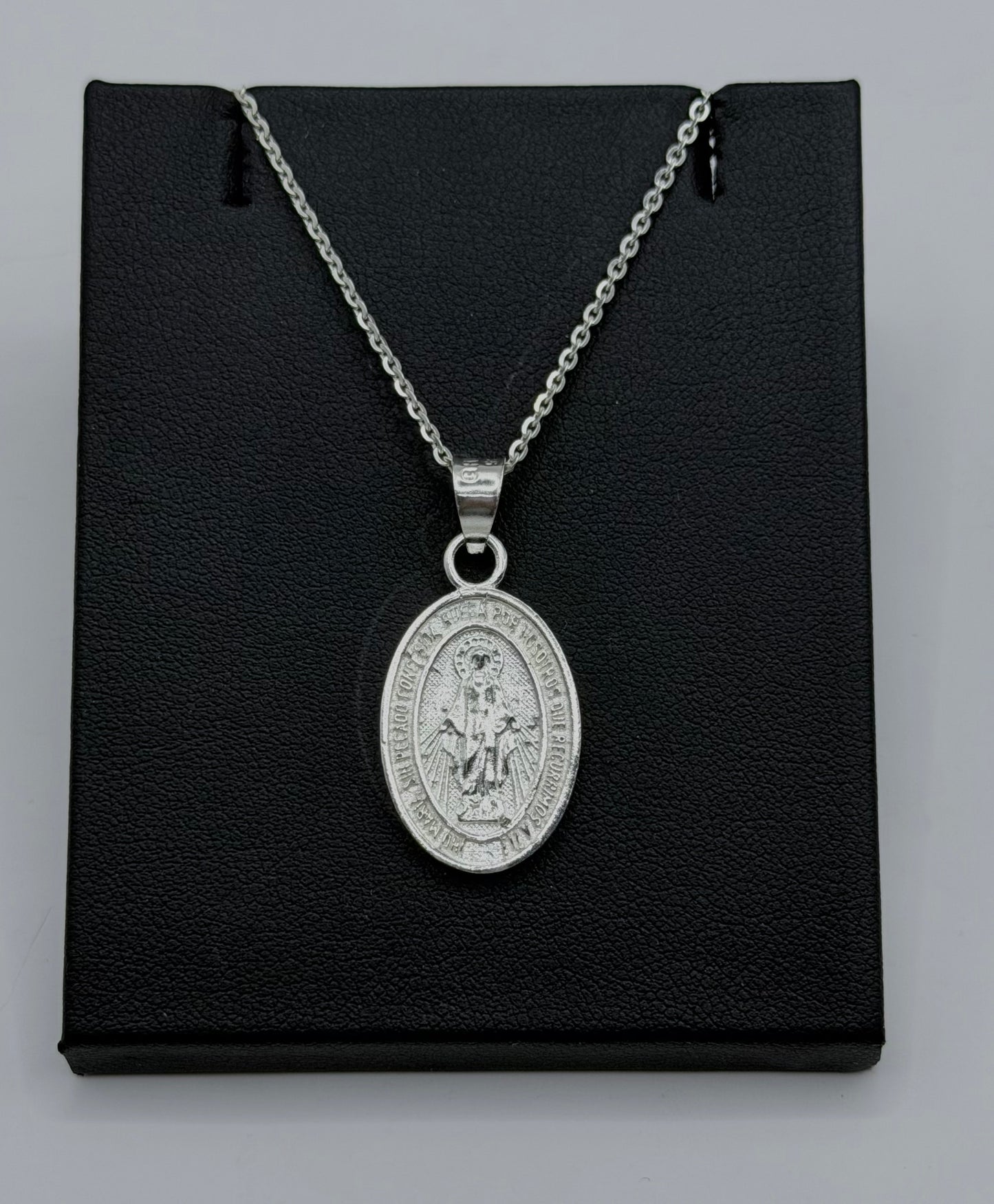 Medalla ovalada de la Virgen María en plata .925, grabada en relieve, colgada de cadena de eslabones de plata sobre fondo negro