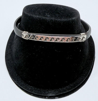 Pulsera de plata .925 con patrón de olas sobre caucho negro, vista frontal en forma de brazalete