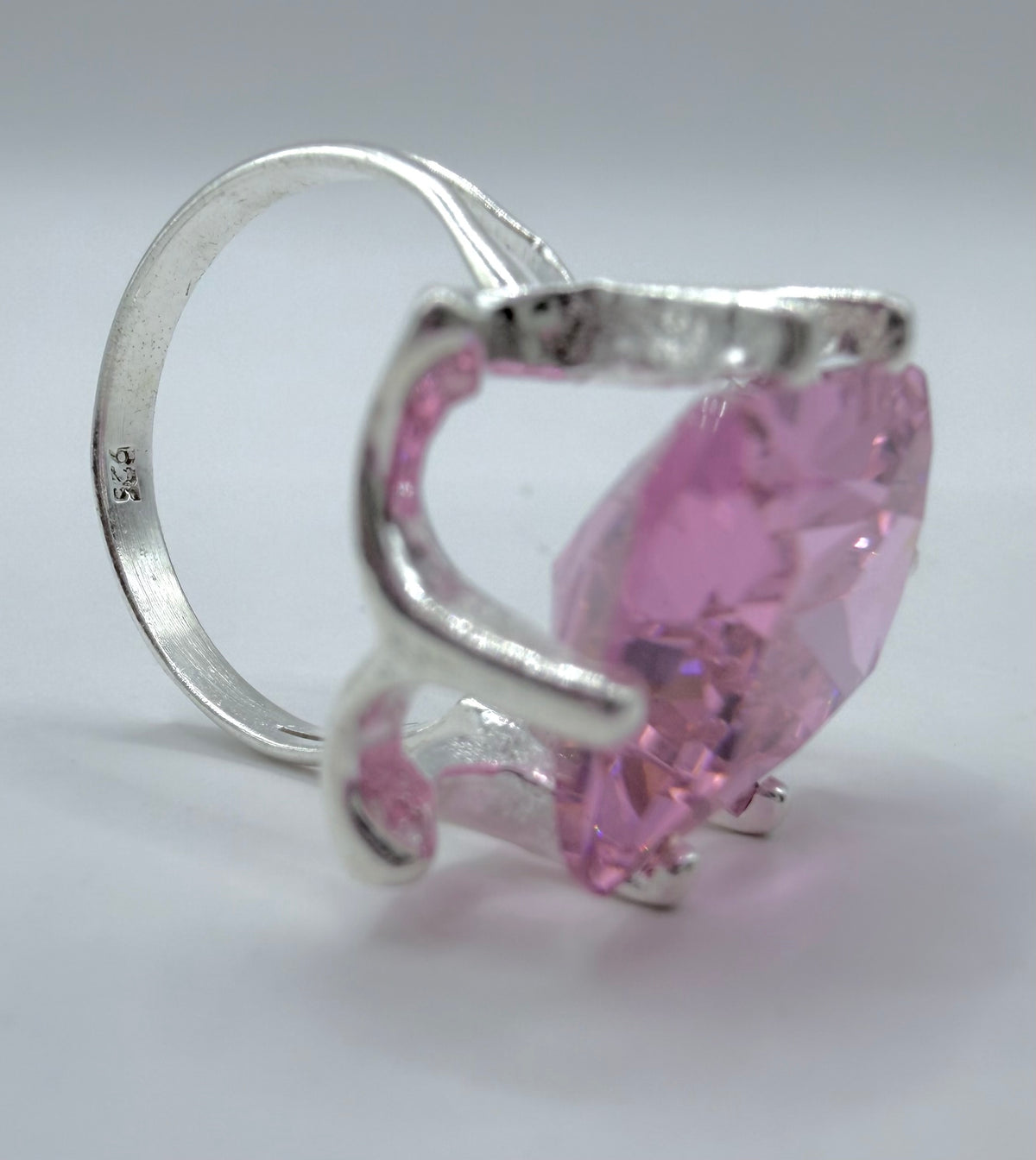 Detalle lateral del anillo mostrando el engaste de prong que sostiene la circonia rosa facetada