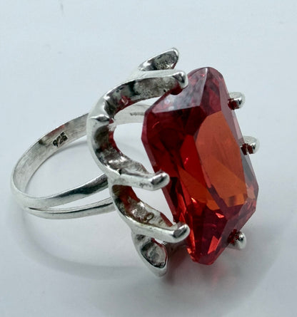 Detalle lateral del anillo tipo caramelo — volumen escultural y piedra roja brillante