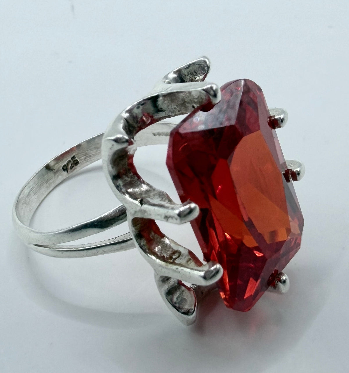 Detalle lateral del anillo solitario circonia roja mostrando engaste seguro en plata pura